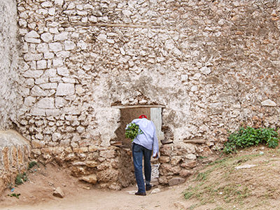 Man carrying chat plant passing through small hyena gate in Harar wall, Ethiopia, photo by Ivan Kralj