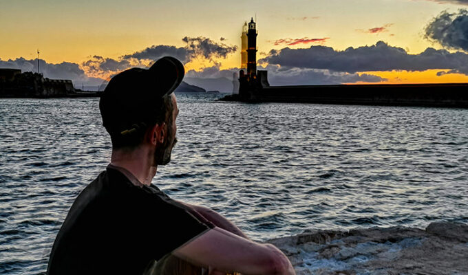Pipeaway blogger Ivan Kralj sitting in the backlight of the sunset behind the lighthouse in Chania, Crete, Greece, photo by Nikos Samartzis