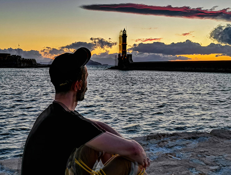 Pipeaway blogger Ivan Kralj sitting in the backlight of the sunset behind the lighthouse in Chania, Crete, Greece, photo by Nikos Samartzis