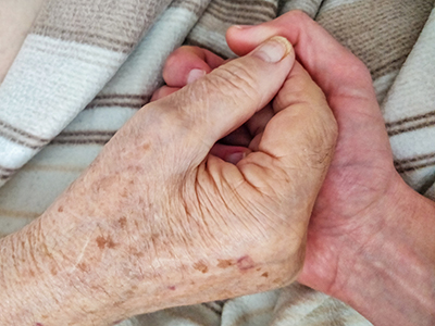 Close-up of father and son holding hands during the palliative care at father's home, photo by Ivan Kralj