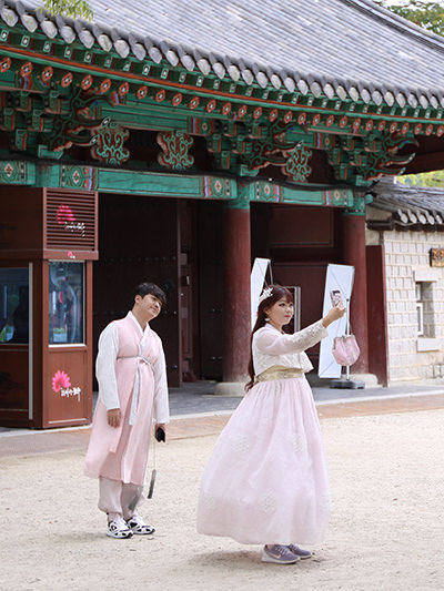 Couple posing for a selfie with physical distance between each other, in front of a temple at Gyeonggijeon shrine in Hanok Village, Jeonju, South Korea, photo by Ivan Kralj