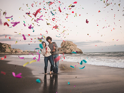 Couple on the beach using two confetti cannons, love photo created by Freepik