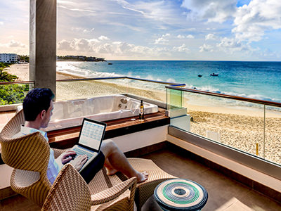 Digital nomad working on laptop on the terrace overlooking the beach in Anguilla, the Caribbean, copyright Anguilla Tourist Board