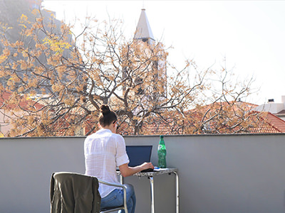 Digital nomad working on laptop outside with Ponda do Sol digital nomad village in the background on Madeira Island, Portugal, copyright Startup Madeira