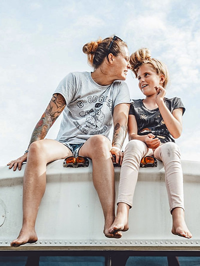 Jessica Rambo and her daughter Skyler sitting on the top of the converted school bus, the Painted Buffalo Traveling Studio