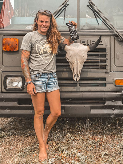 Jessica Rambo, American Marine Corps veteran and artist, standing next to the buffalo skull in front of her tiny house on wheels, the Painted Buffalo Traveling Studio