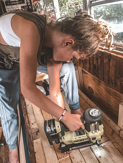 Jessica Rambo working with a tool, converting a school bus into a tiny house on wheels