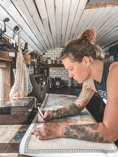 Jessica Rambo mapping her road trip inside of the Painted Buffalo Traveling Studio, a tiny house on wheels she built by herself out of a retired school bus