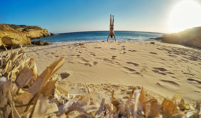Travel blogger Ivan Kralj doing a handstand on a sandy beach in Donousa, Greece, photo by Ivan Kralj