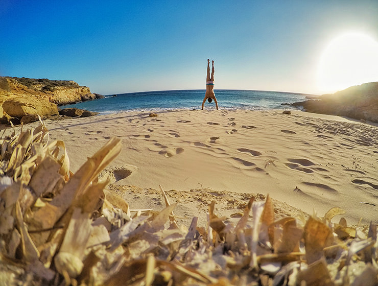 Travel blogger Ivan Kralj doing a handstand on a sandy beach in Donousa, Greece, photo by Ivan Kralj