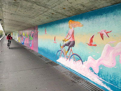 A bicyclist riding a bike next to a mural of a bicyclist on the Schwarzwaldbrücke bridge, one of the things to do in Basel, Switzerland, if you are into street art. Photo by Ivan Kralj