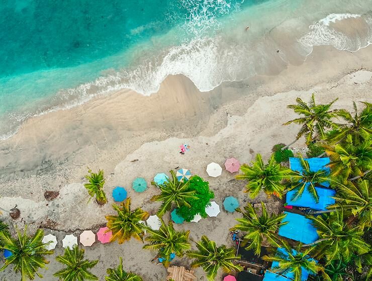 Aerial view of sea and sandy beach with palms and parasols in Bali, Indonesia, one of the top destinations to visit in 2022 according to travel trends, photo by carlesrgm / Depositphotos.com