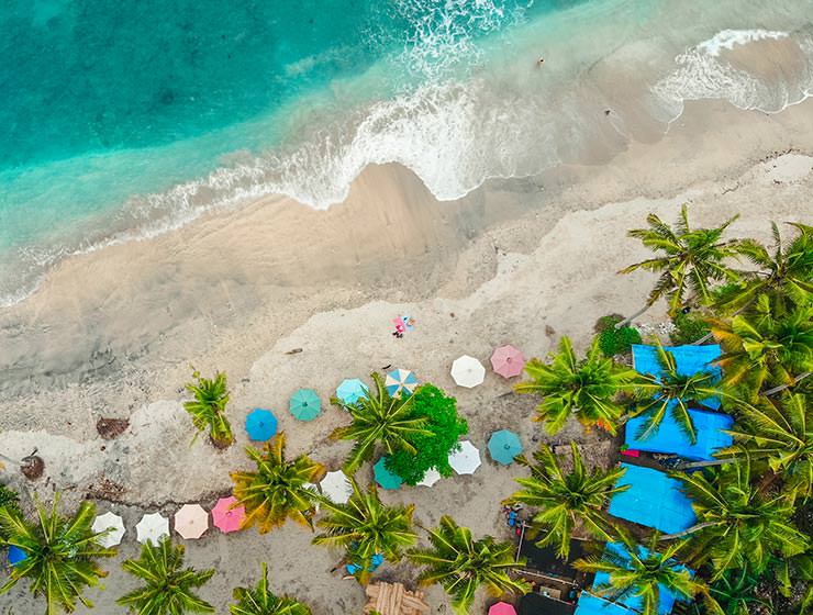 Aerial view of sea and sandy beach with palms and parasols in Bali, Indonesia, one of the top destinations to visit in 2022 according to travel trends, photo by carlesrgm / Depositphotos.com