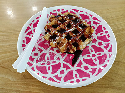 Waffle with chocolate served on a ceramic plate with plastic utensils at The Spa in Garden 5, a jjimjilbang in Seoul, South Korea, photo by Ivan Kralj