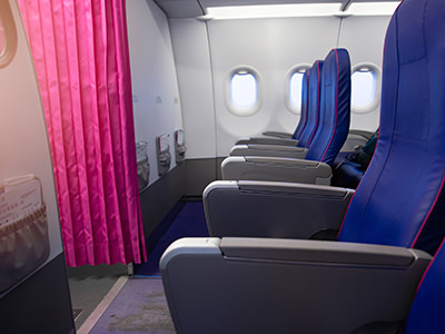 First row of economy class on a plane, the so-called bulkhead seats, divided from the rest of the aircraft with a pink curtain, photo by Djedzura, Depositphotos.com