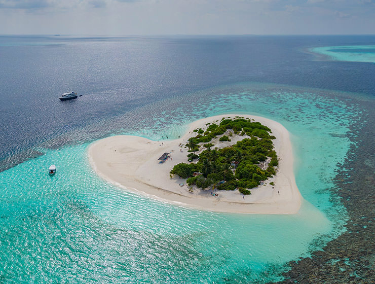 Panoramic view of tropical island shaped like a heart in the blue sea of the Maldives, photo by Vitaliy Sokol, Depositphotos