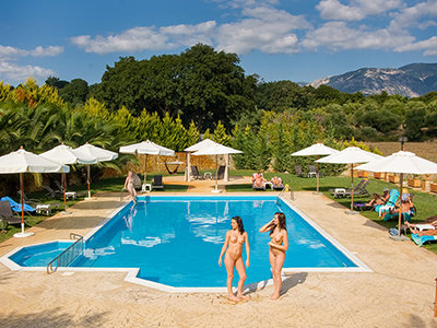 Naked women standing by the swimming pool at Vassaliki Naturist Club in Kefalonia, one of the best clothing-optional resorts in Greece, photo by Vassaliki