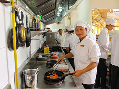 A young student cooks at the stove of Spoons, a social enterprise in Siem Reap, Cambodia, that enables culinary education to underprivileged young adults, photo by Ivan Kralj