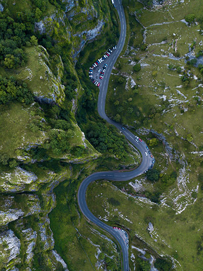 Aerial view of curvy Atlantic Highway in England, UK, with cars parked at the roadside, photo by Ryan Searle, Unsplash