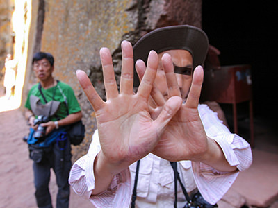 Chinese photographer hiding behind his hands, after he was obsessively taking photographs of churchgoers at Bete Giyorgis church in Lalibela, Ethiopia, and then was caught on camera of Pipeaway blogger Ivan Kralj who decided to "fight fire with fire", and turned the lens toward the perpetrator