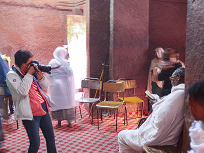 Chinese photographer taking a short of a man in prayer at Bete Giyorgis, a church in Lalibela, Ethiopia, photo by Ivan Kralj