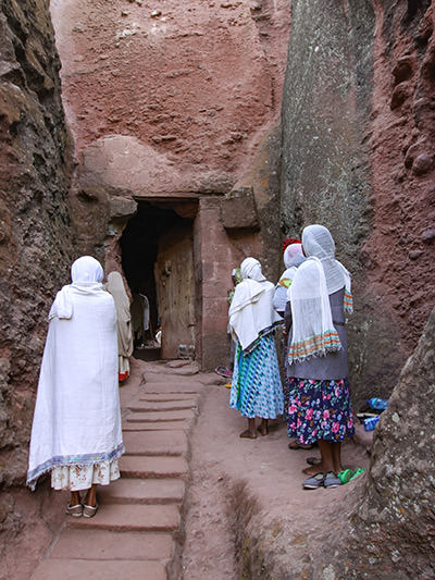 Women standing and praying in front of the entrance to Bete Giyorgis, a church in Lalibela, Ethiopia, photo by Ivan Kralj