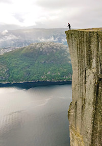 Man looking over the edge of the Preikestolen cliff in Norway, photo by Ivan Kralj