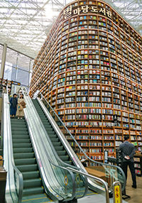 Humongous shelves of Starfield Library in Seoul, South Korea, with people riding an escalator, photo by Ivan Kralj