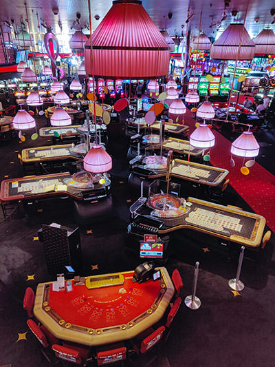 The interior of Casino Barriere in Montreux, Switzerland, with a variety of casino games on offer to the visitors under pink chandeliers, photo by Ivan Kralj.