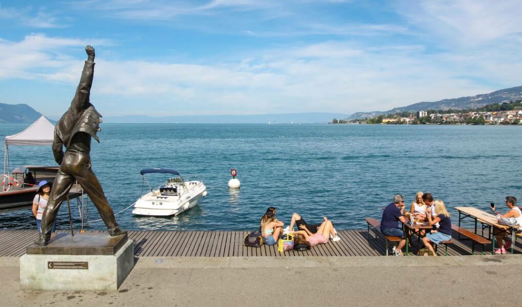Panorama of Lake Geneva in Montreux with Freddie Mercury statue in the front and people chilling at the promenade, photo by Ivan Kralj.