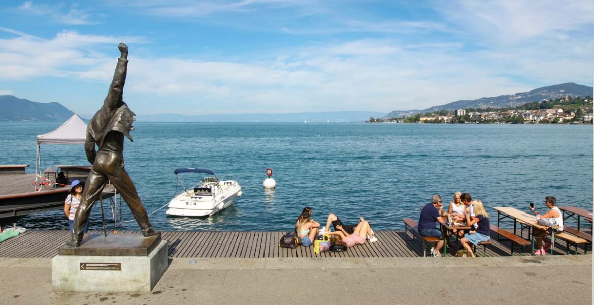 Panorama of Lake Geneva in Montreux with Freddie Mercury statue in the front and people chilling at the promenade, photo by Ivan Kralj.