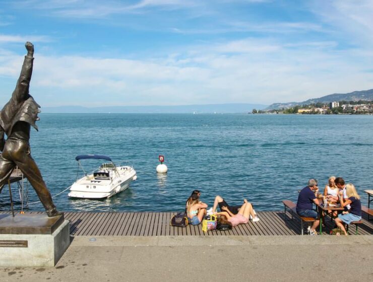 Panorama of Lake Geneva in Montreux with Freddie Mercury statue in the front and people chilling at the promenade, photo by Ivan Kralj.