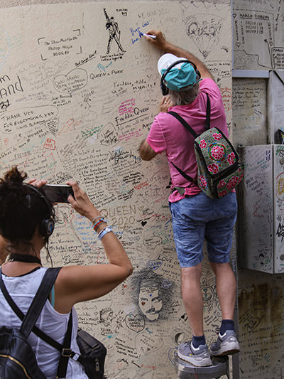 A fan writing a message on Queen Tribute Wall in Montreux, Switzerland, photo by Ivan Kralj.