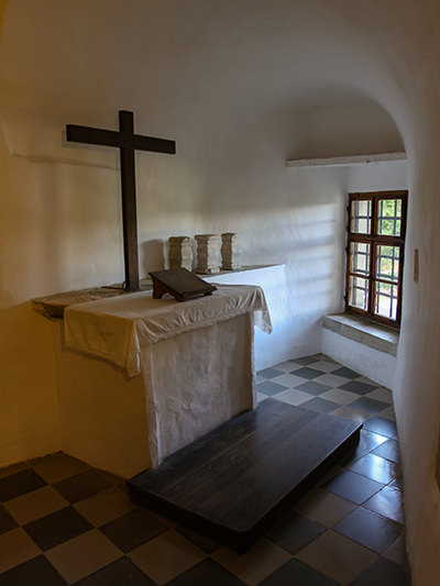 A wooden cross and altar in a small chapel inside of Predjama Castle, Slovenia, photo by Ivan Kralj.