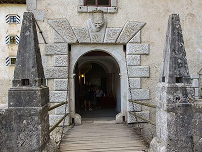 Drawing bridge with two stone pyramids at the entrance to Predjama Castle, Slovenia, photo by Ivan Kralj.