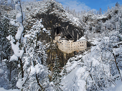 Predjama Castle in the mountainside during winter, surrounded by snow, credit: Postojna Cave Park, Slovenia.