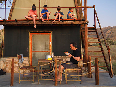 Sebastien Pelletier and his four children eating a meal in front and on the top of a hut in Africa, on the family's world voyage before children lose their vision, photo by Edith Lemay