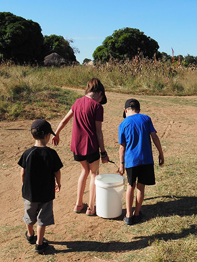 Edith Lemay's children carrying a bucket full of water in Africa, photo by Edith Lemay