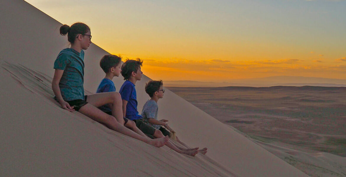 Lemay-Pelletier family's children gazing into distance while seated on a sand dune, on a world trip before losing they lose their eyesight due to retinitis pigmentosa genetic disorder, photo credit Edith Lemay