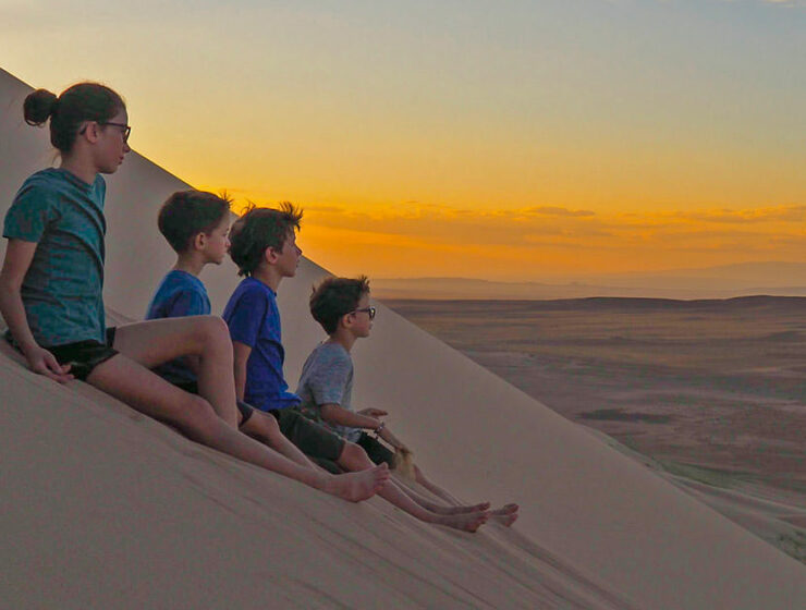 Lemay-Pelletier family's children gazing into distance while seated on a sand dune, on a world trip before losing they lose their eyesight due to retinitis pigmentosa genetic disorder, photo credit Edith Lemay