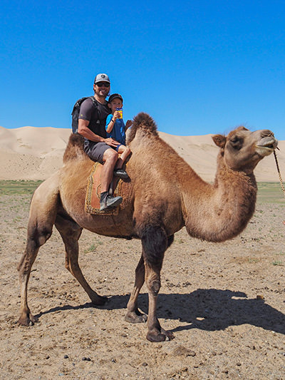 Laurent, a five-year-old that wanted to drink a juice on camel, having his wish granted; here pictured with his father Sebastien Pelletier riding a camel together on the world trip before the boy and his siblings lose their eyesight due to a genetic condition, photo by Edith Lemay