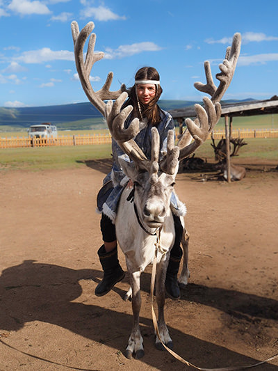 Mia Pelletier, riding a reindeer in Mongolia, during her family's world voyage that should fill her visual memories before she loses her eyesight, photo by Edith Lemay