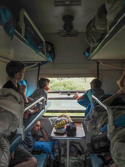 Sebastien Pelletier with his four children lying in bunk beds and looking outside of Tazara (Tanzania-Zambia Railway) train, on their world trip before children lose their eyesight, photo by Edith Lemay