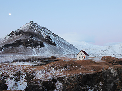 House in a mountainous snowy landscape of Arnarstapi, Iceland, photo by Tom Vining, Unsplash.com.