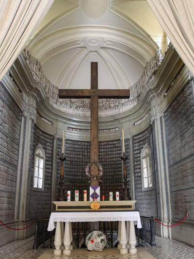 Altar with big cross in the Ossuary church in Solferino, Italy, with back wall of the apse covered in human skulls, photo by Ivan Kralj.