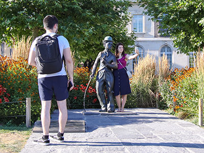 Woman taking a selfie while standing next to Charlie Chaplin's statue in Vevey, Switzerland, photo by Ivan Kralj.