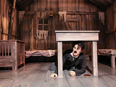 The wax figure of the Little Tramp, hiding under a table, at the movie set of "The Gold Rush" in Charlie Chaplin's World, museum in Vevey, Switzerland, photo by Ivan Kralj.