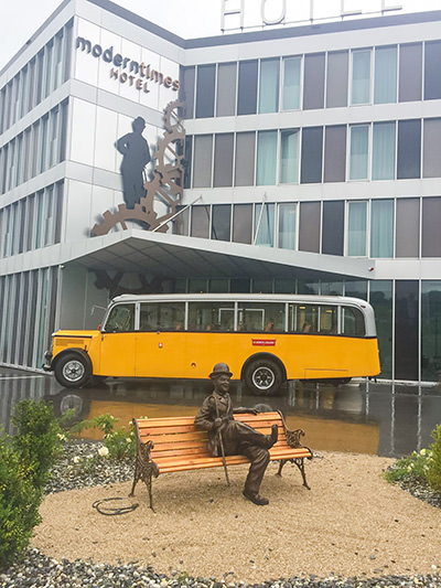 Wooden bench with a statue of Charlie Chaplin in front of the Modern Times Hotel in Vevey, Switzerland.