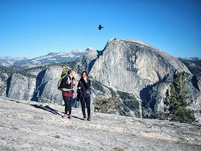 Two young women hiking in the Yosemite National Park with a mountain as a backdrop, photo by Kelly Repreza, Unsplash.
