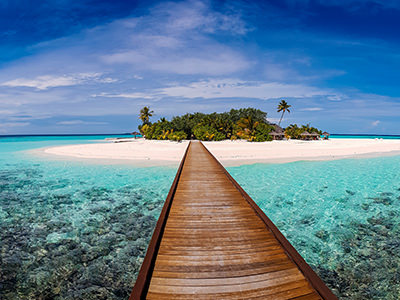 Wooden dock leading to an island with a white sand beach in Maldives, Maafushivaru, photo by Mohamed Thasneem, Unsplash.